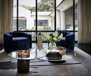 Living room nook with round glass coffee table and dark blue accent chairs