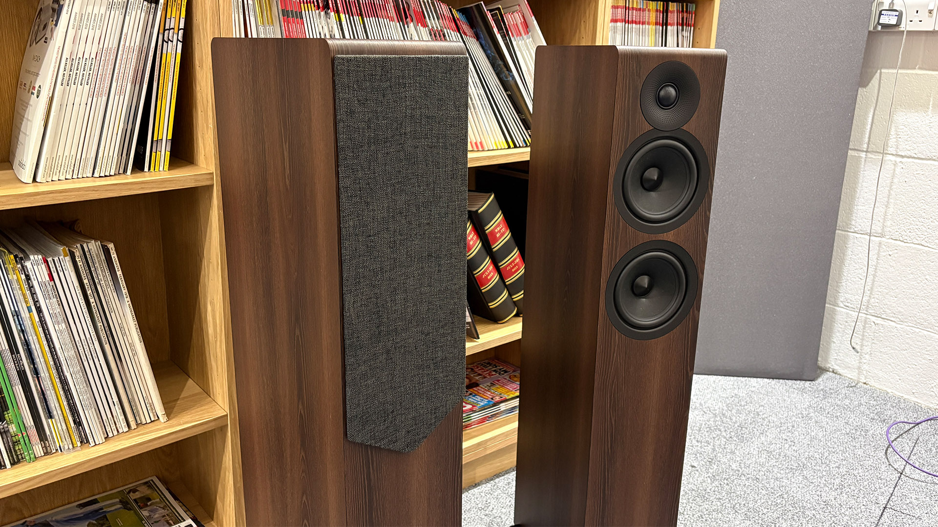Acoustic Energy AE309 Mk2 floorstanding speakers in front of bookcase, one has baffle attached