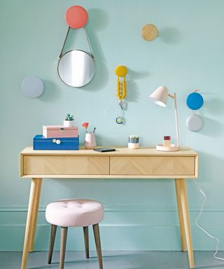 Dressing room with wooden dressing table and colourful painted dots on wall to hang mirrors and accessories