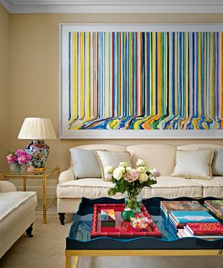 cream living room with cream sofas and statement multicolored artwork and blue coffee table