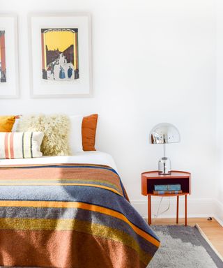 white bedroom with orange striped bedding and silver bedside table lamp