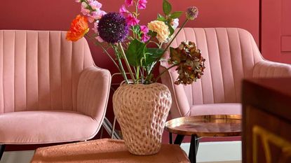 Strawberry vase pink on table with two pink sofas next to 