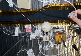 Astronauts aboard the space station 3D printed a shield to cover one of the two Radiation Environment Monitors (REMs) inside the BEAM habitat. The shield, the white hemisphere at the center of the photograph, is shown inside the BEAM module. In the coming months, the crew will print successively thicker shields to determine the shield's effectiveness at blocking radiation.