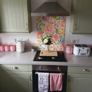 pastel kitchen with green painted cupboards and oven with floral splashback