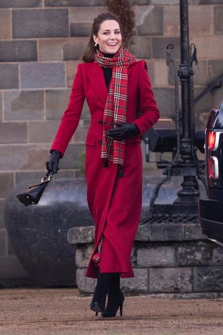 Kate Middleton wears a red coat and scarf, with black boots as she visits Cardiff Castle as part of their working visits across the UK ahead of the Christmas holidays on December 8, 2020