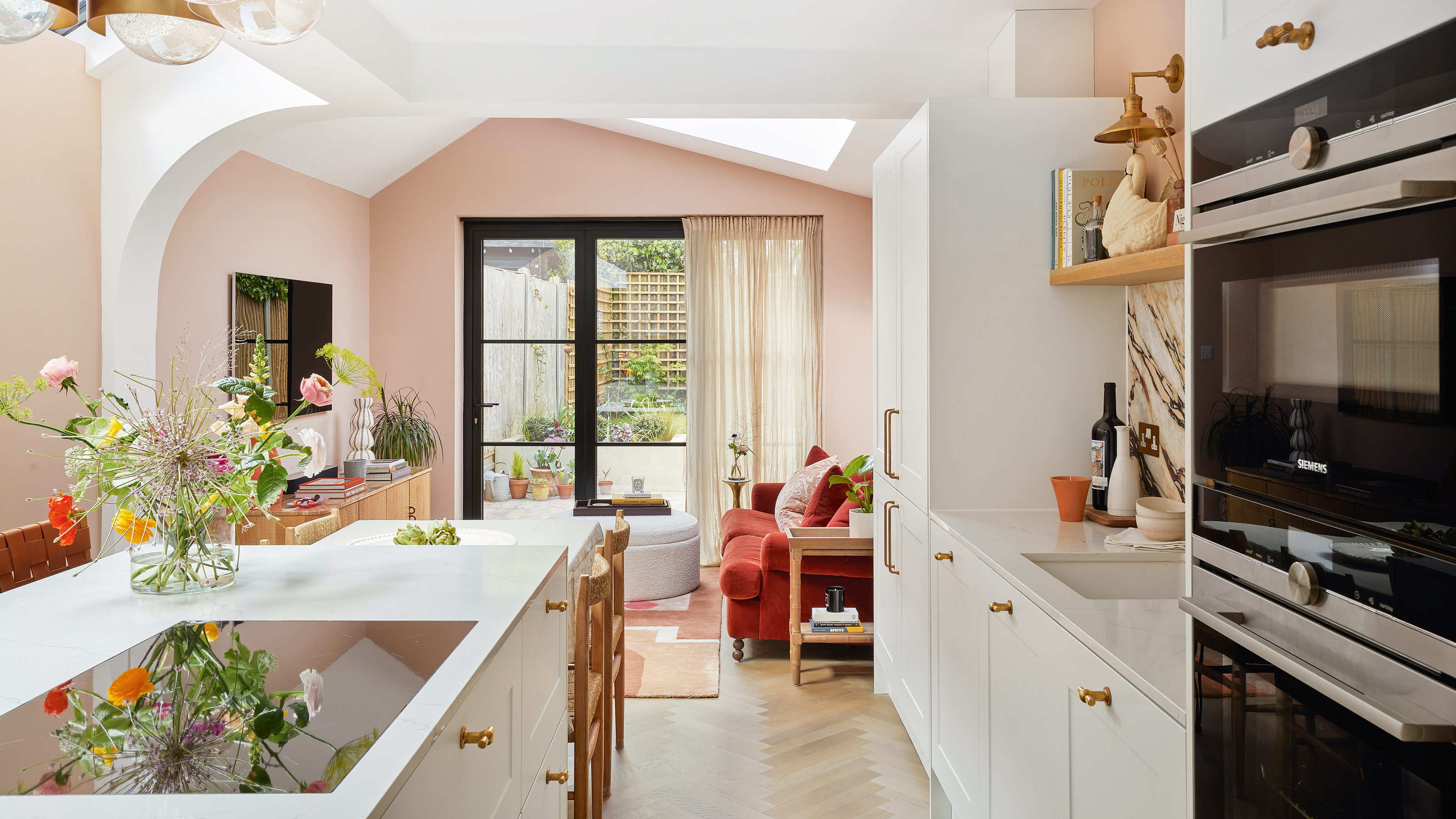 an open plan kitchen dining living area with patio doors leading out into a garden