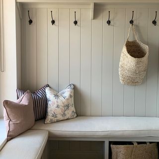 A wall-panelled small hallway with coat hooks, a built-in bench and storage baskets