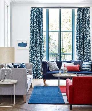 A living room curtain idea with white walls, dark blue patterned curtains and blue and red furniture