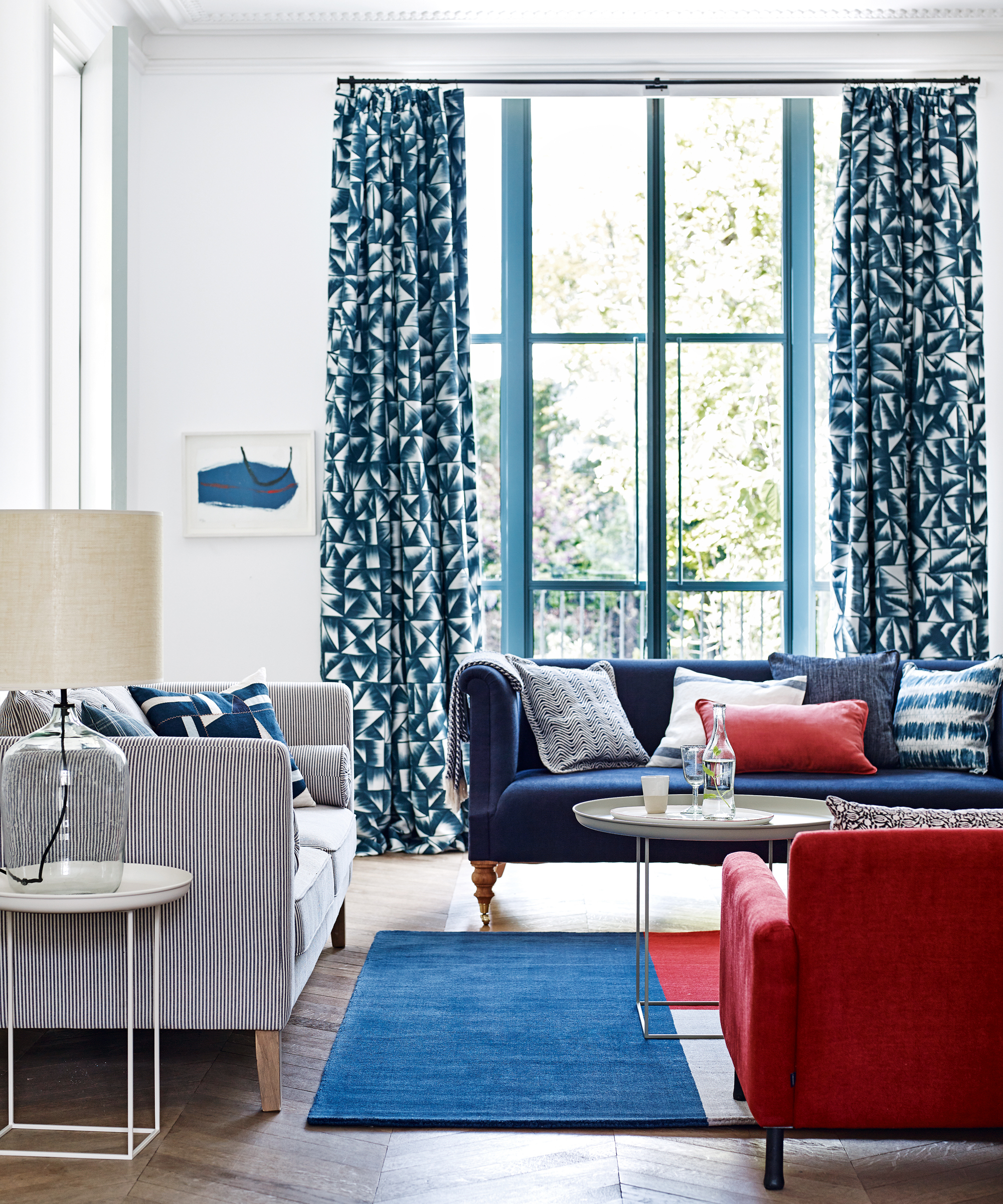 living roomwith white walls, dark blue patterned curtains and blue and red furniture