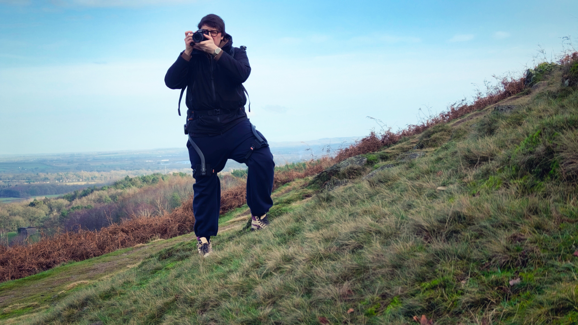 Person using a Hypershell X Ultra exoskeleton on a grassy hill