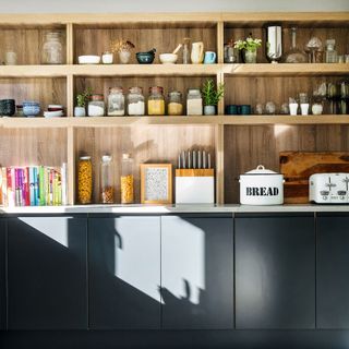 Fitted kitchen with a wall of storage shelves and dark grey units
