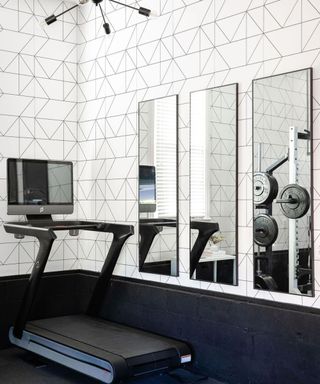 A home gym with peel and stick adhesive white wallpaper, treadmill and trio of mirrors
