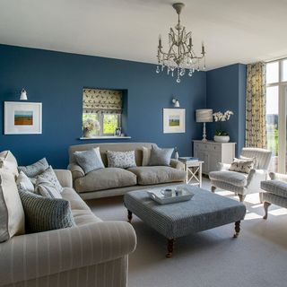 living room with blue wall grey sofa with cushions chandelier and frames