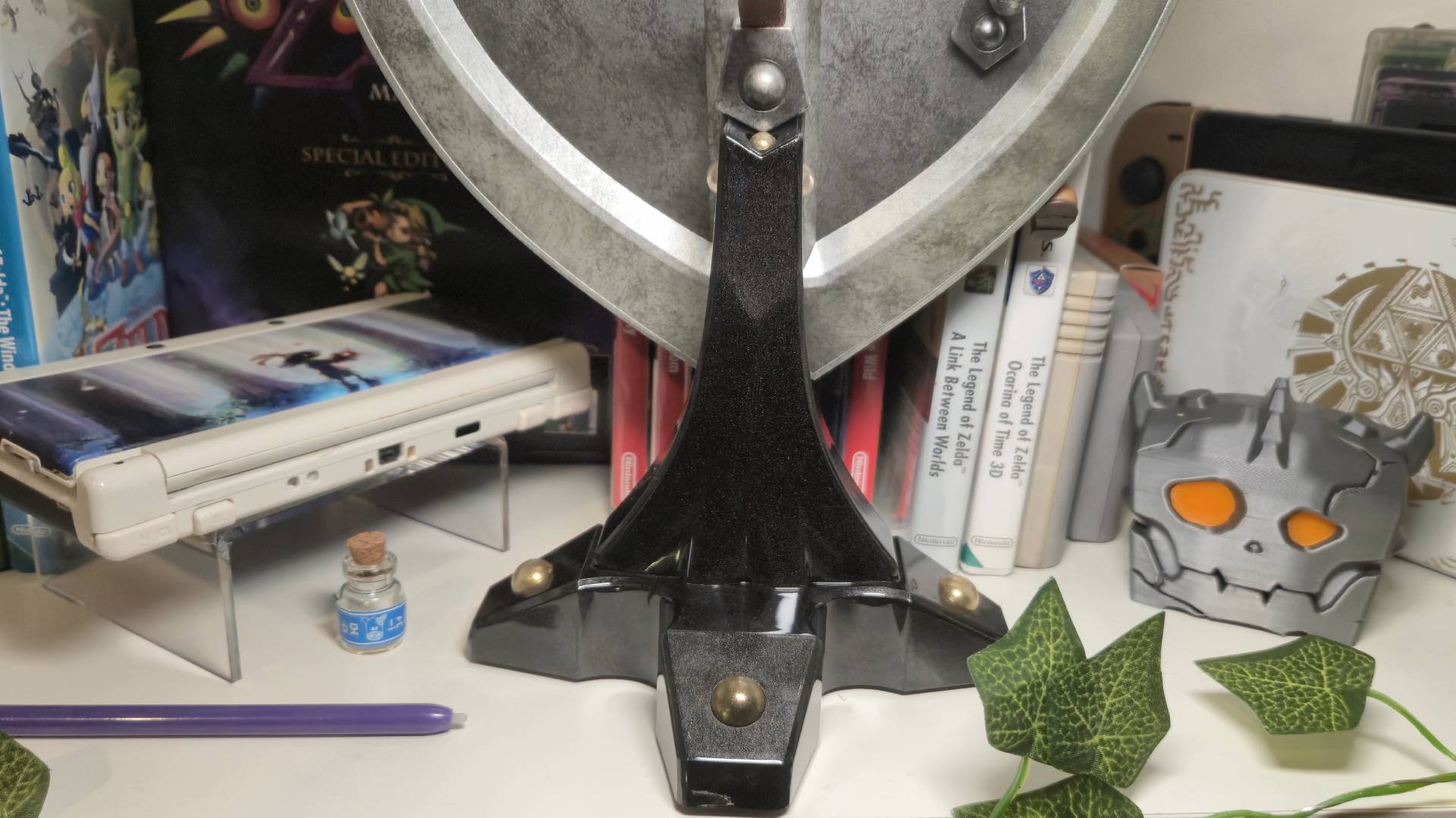 Close up of the stand of the F4F Hylian Shield sitting amongst other Zelda merch.