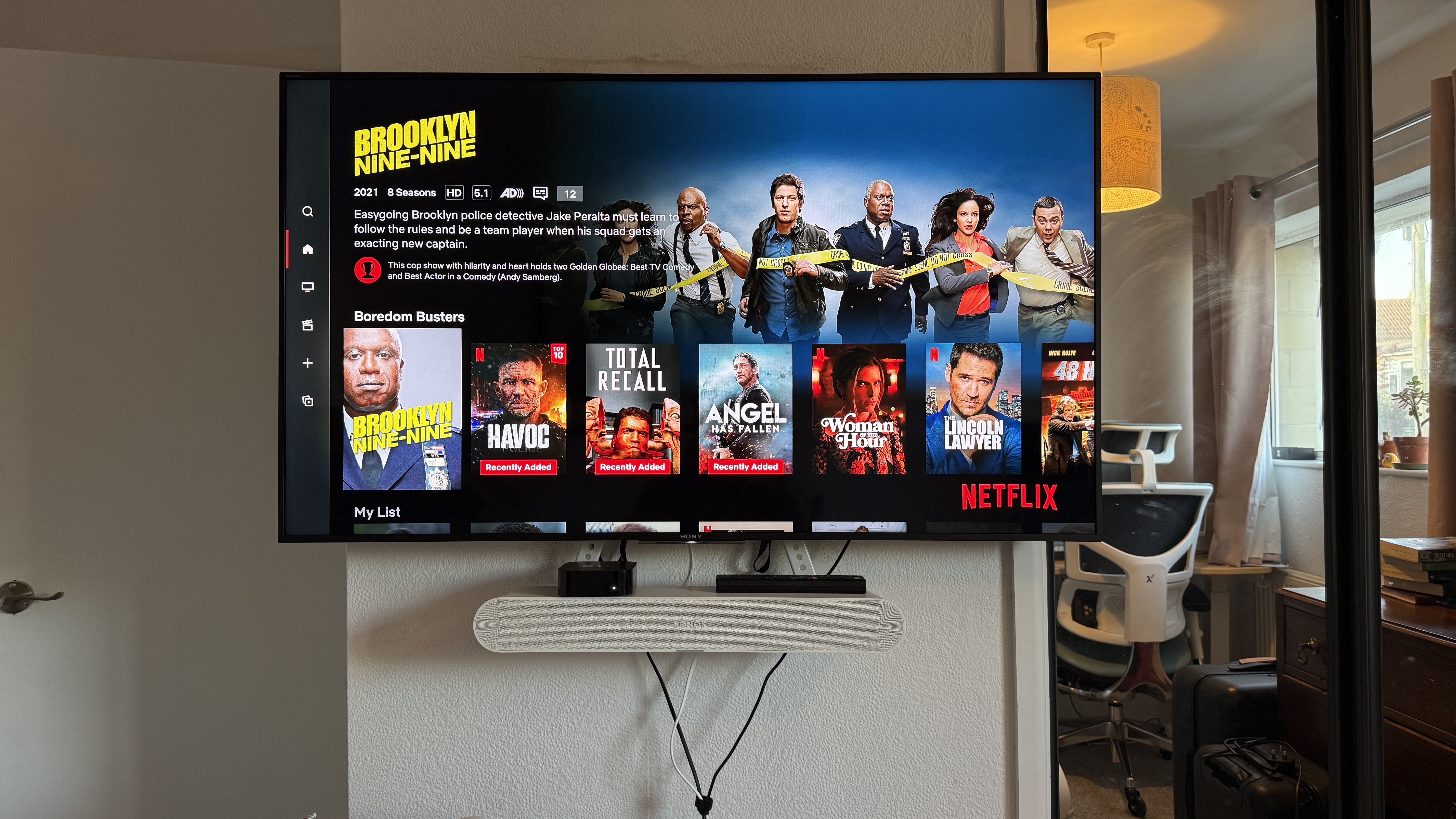 A Sony TV mounted on a wall, with a Sonos soundbar underneath it