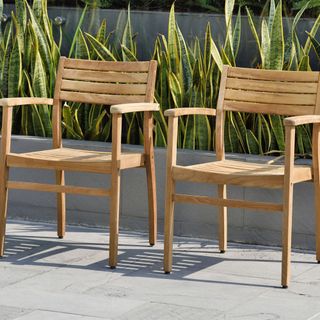 set of two stackable teak outdoor chairs on a patio