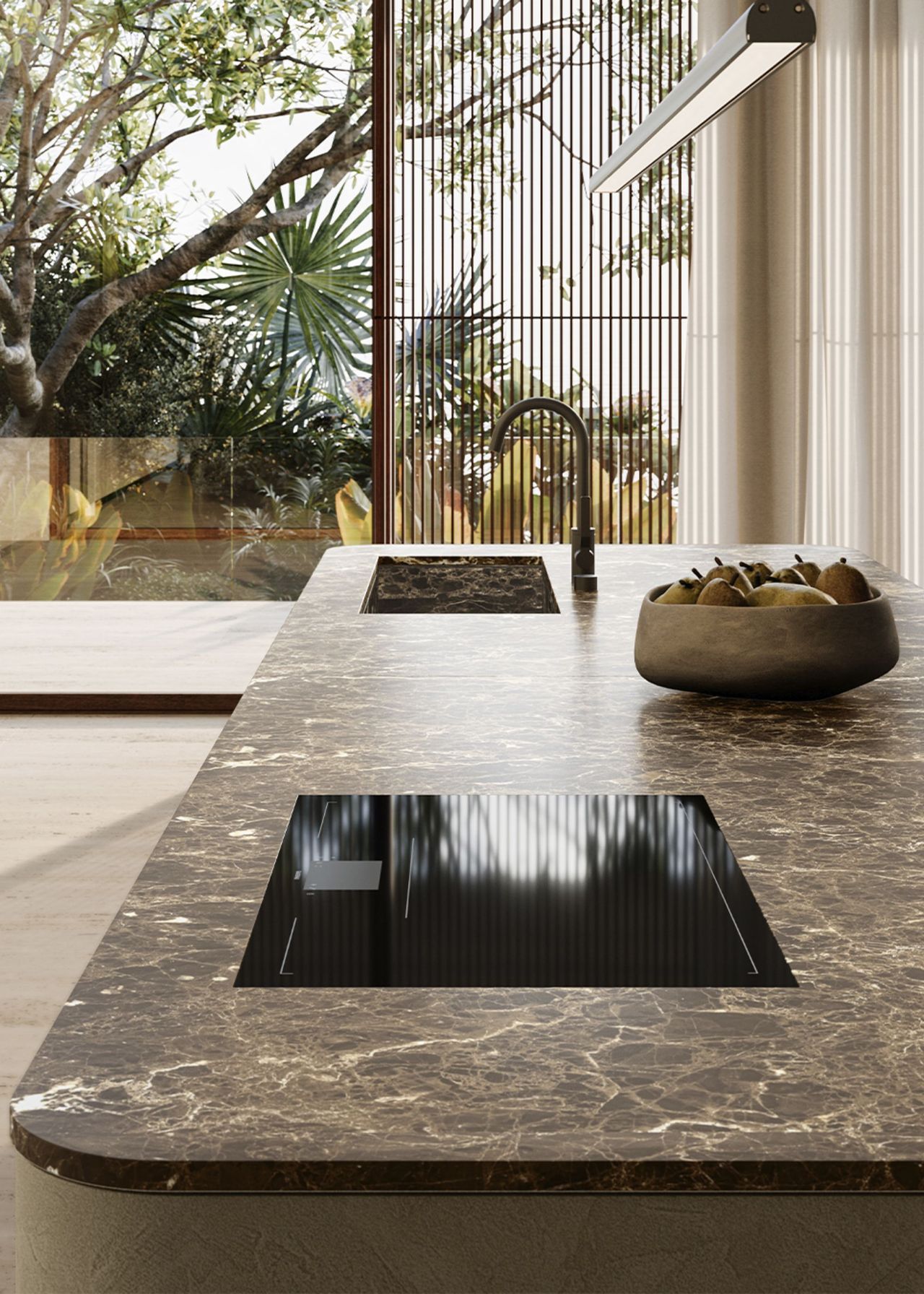 A marble kitchen island with a hob on top and a sink/tap. There is also a bowl of fruit.