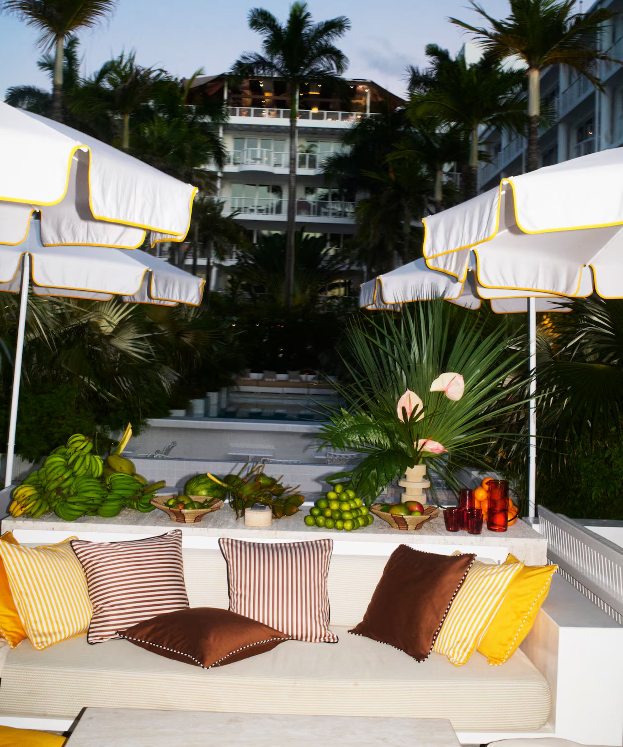 Banquette seating outside with brown and yellow striped cushions and white and yellow parasols