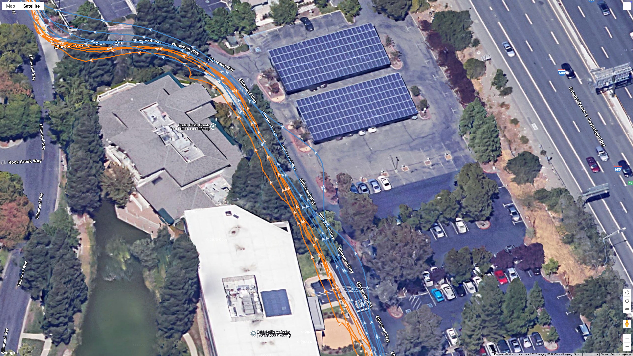 A Google Earth satellite map showing the GPS path of the Samsung Galaxy Watch 8 Classic (blue) and Garmin Forerunner 970 (orange) worn by the same runner.