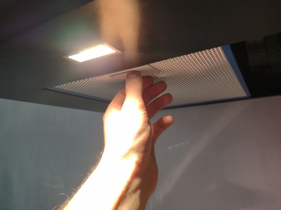 A man's hand fitting an extractor into a cooker hood