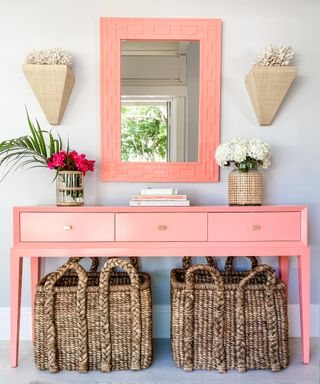 entryway with pink console table, pink mirror and large storage baskets