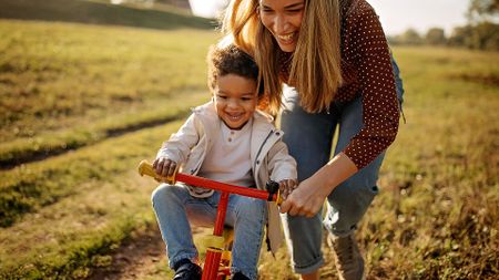 Mother teaching her son to drive a bike.