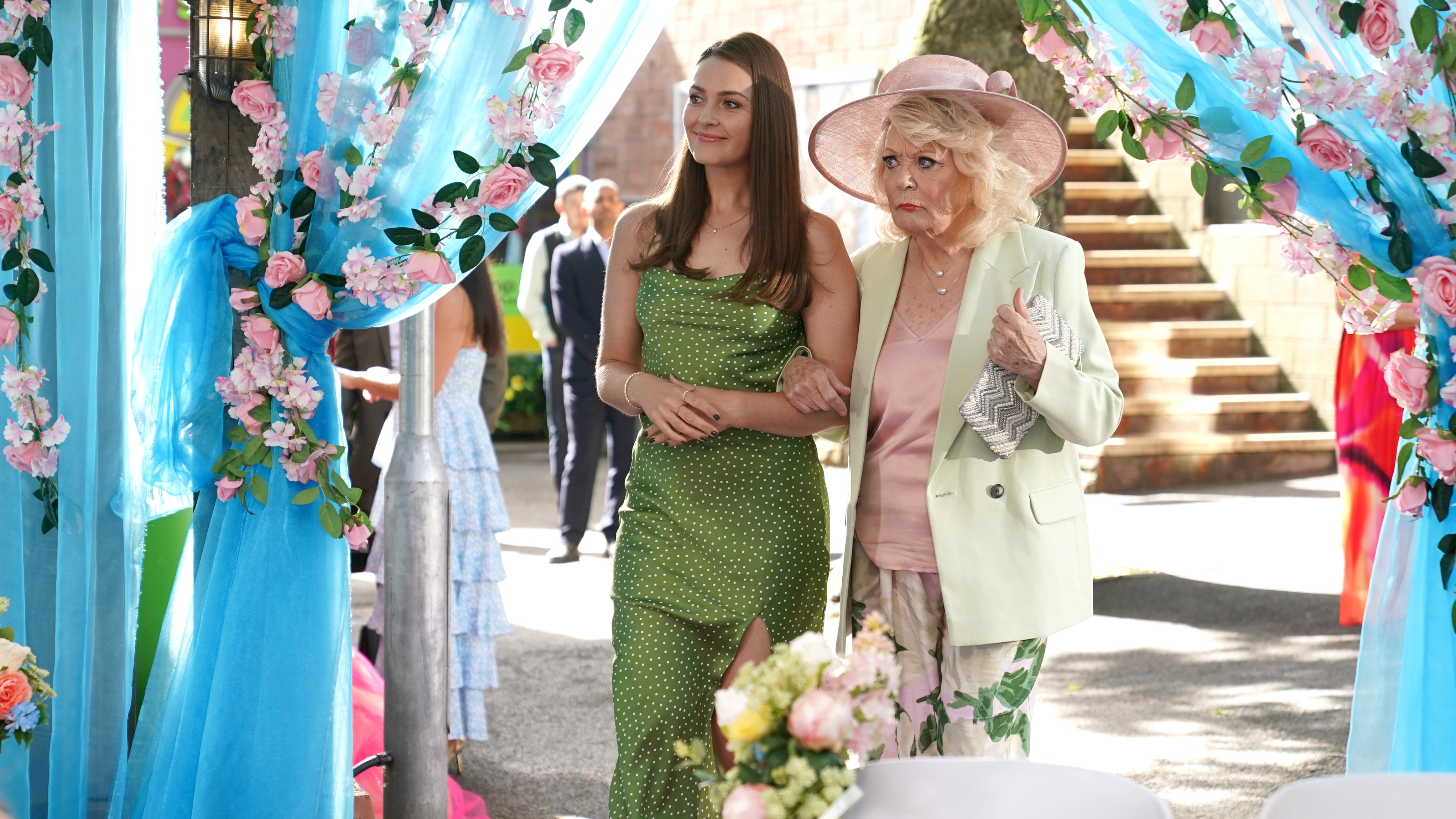 Sienna and Martha walk arm-in-arm together to Jez and John Paul's wedding.