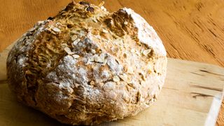 how to make soda bread: a loaf of soda bread with raisins on a chopping board