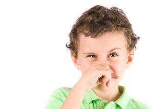 A little boy coughs and wipes his nose.