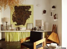 a room with a shelf filled with art with a neon yellow skirt underneath