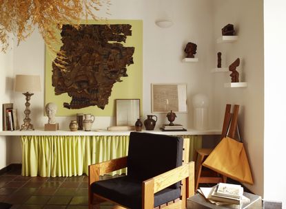 a room with a shelf filled with art with a neon yellow skirt underneath