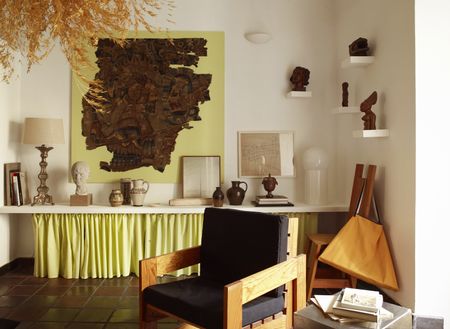 a room with a shelf filled with art with a neon yellow skirt underneath