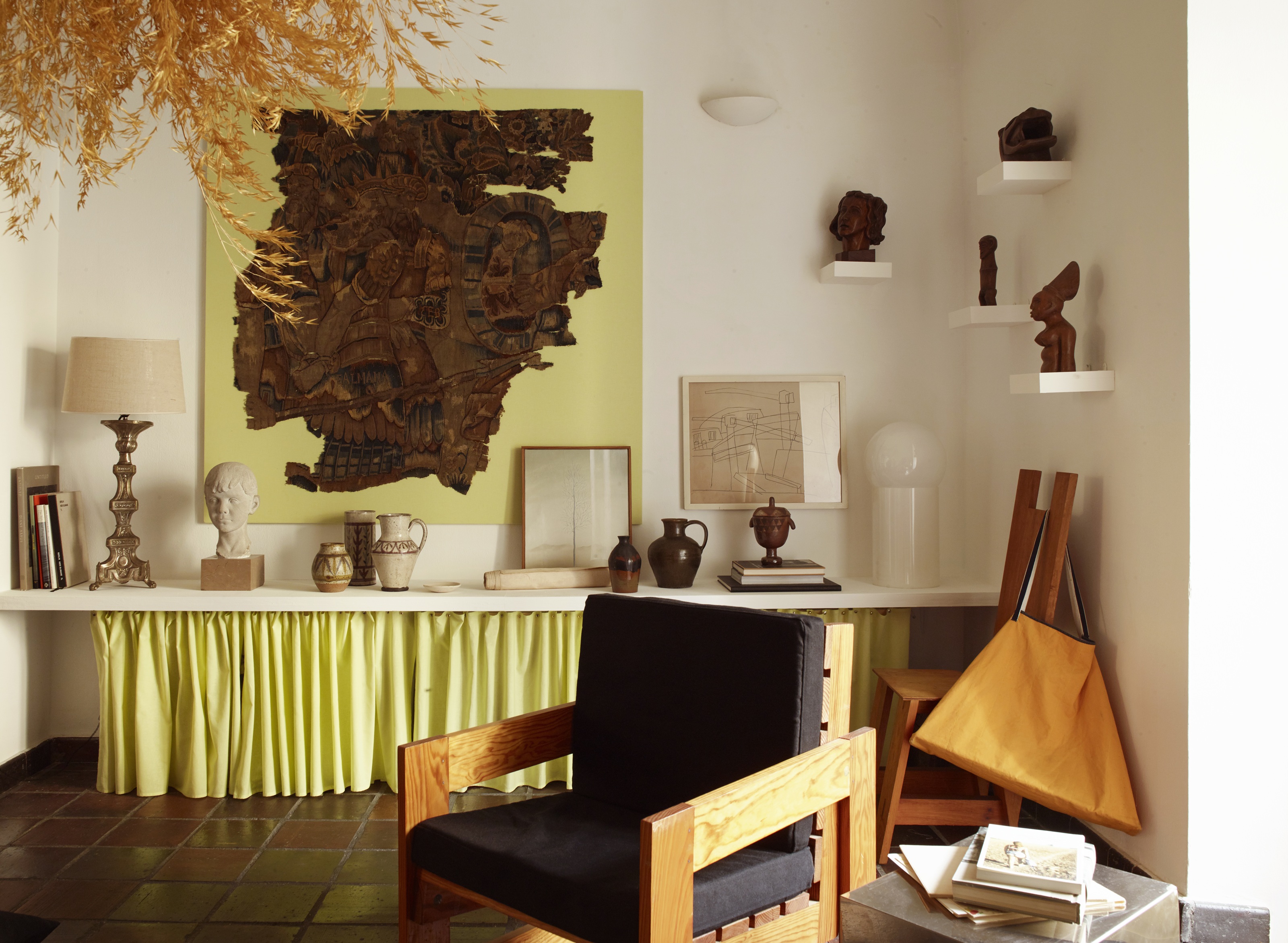 a room with a shelf filled with art with a neon yellow skirt underneath