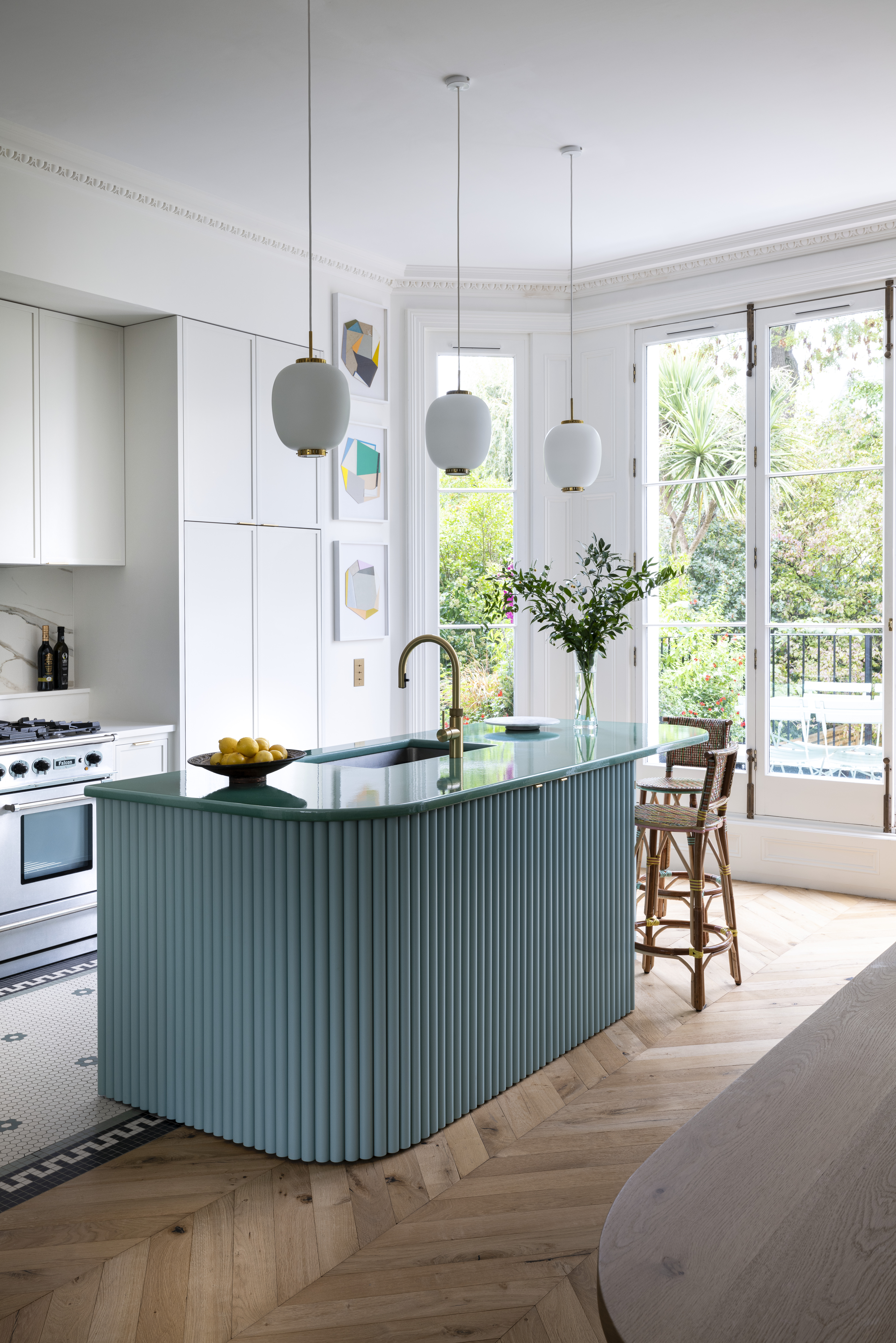 A kitchen designed with white walls, white pendant lights, and a turquoise countertop