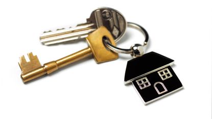 House keys with a house key chain sit on a white surface.