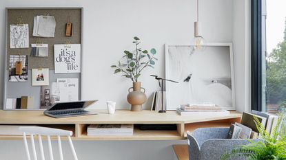 Home office desk setup, patterned wallpaper, velvet desk chair and decorated shelving