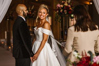 Image of bride and groom holding hands in front of officiant