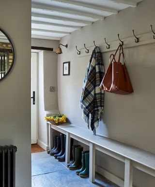 neutral boot room with a stone floor and a coat hook and bench