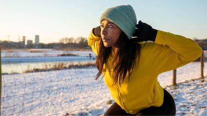 woman in yellow fleece trains outdoors in the snow