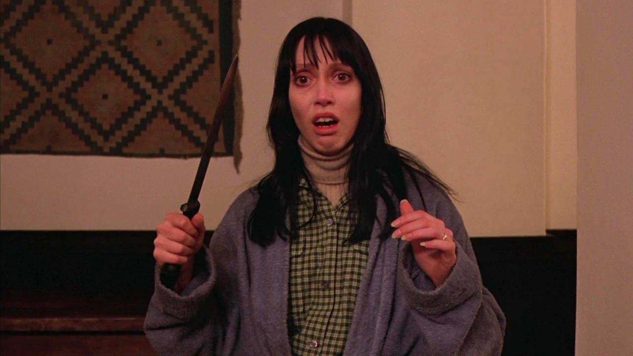 shelly duvall holds a weapon and looks scared in a still from the shining