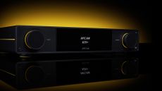 Arcam A25+ integrated amplifier on a reflective tabletop with yellow lit background