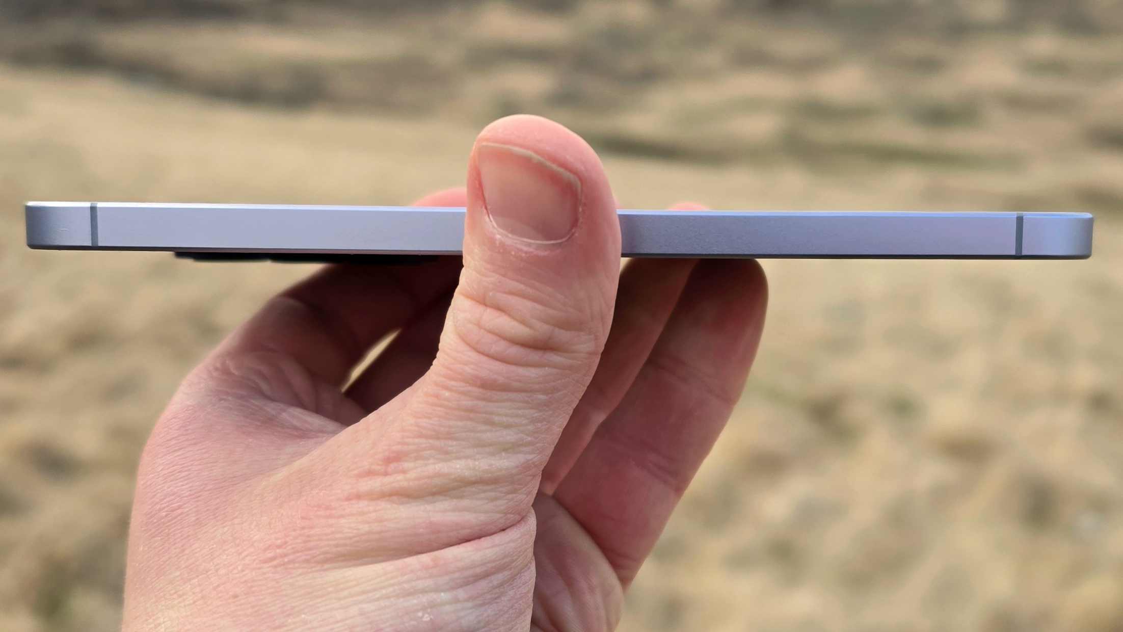 The Samsung Galaxy A57 being held flat to show its thickness.