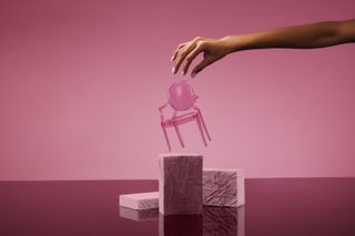 Hand reaches for Barbie and Kartell doll-size pink chair