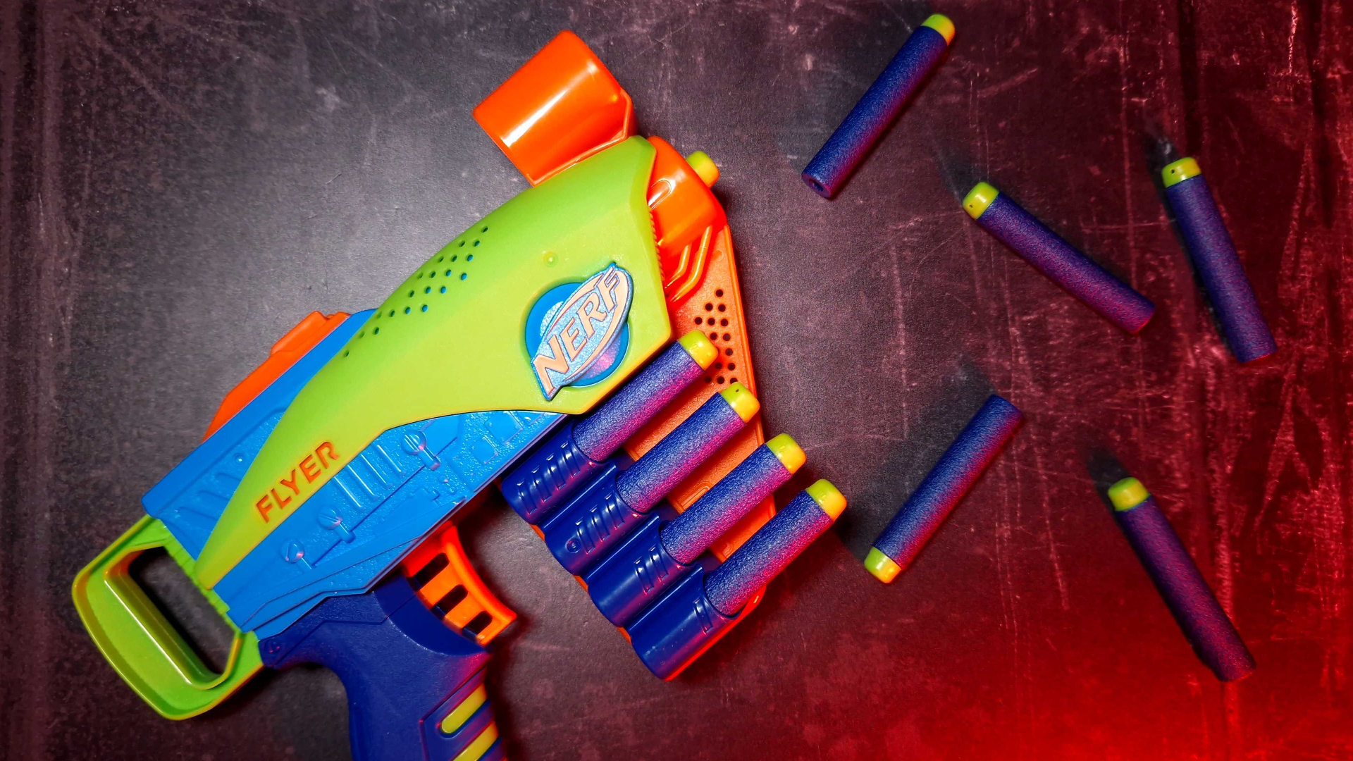 Ein Nerf Elite Jr. Flyer, der neben Nerf Elite Darts sitzt