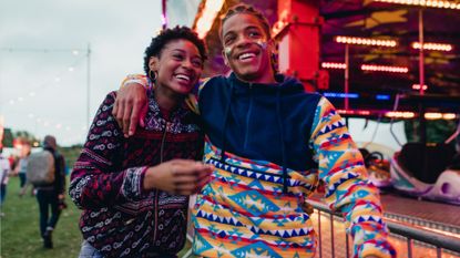 Young couple are laughing and talking as they walk around a funfair on a date