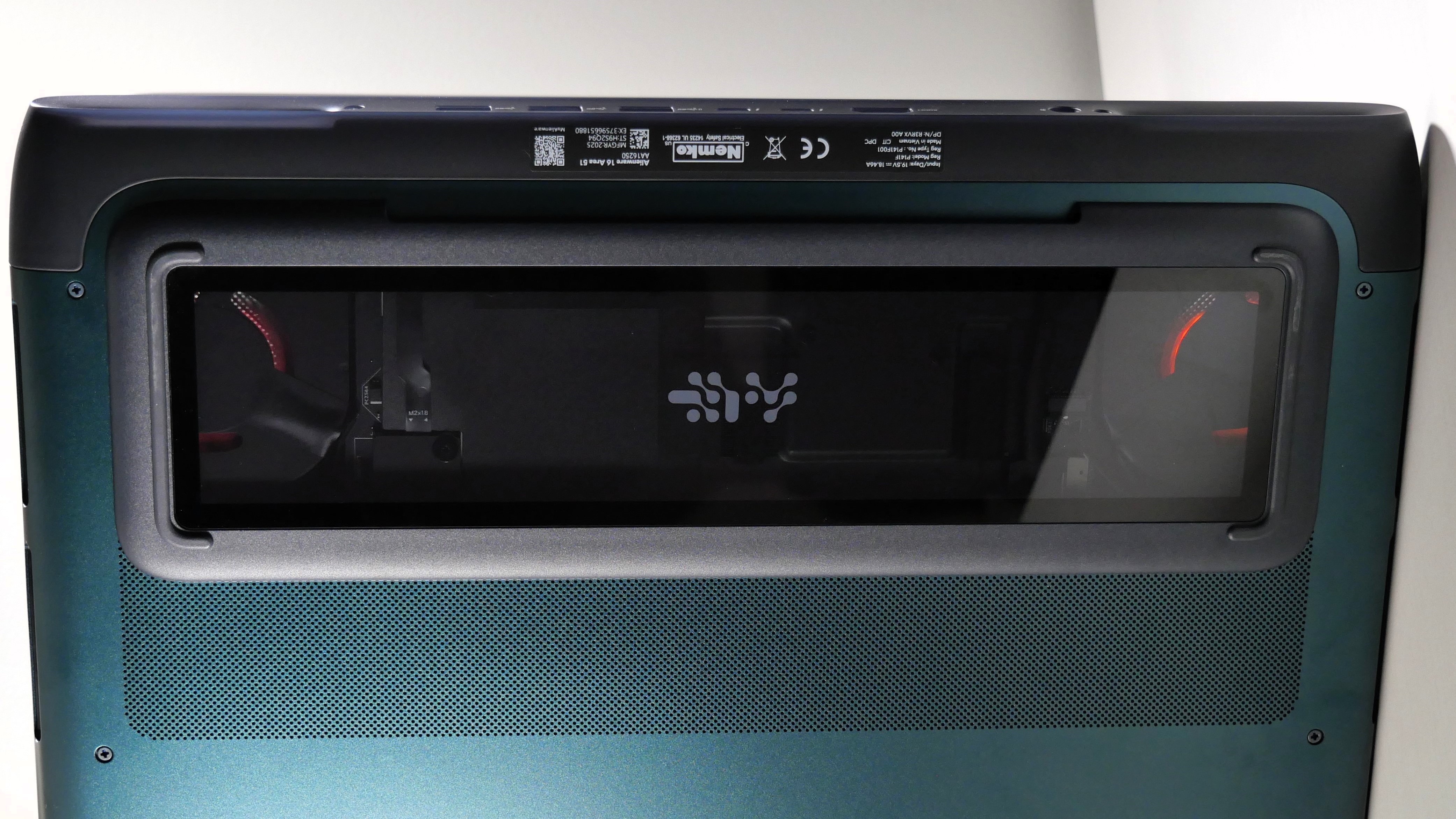 Alienware 16 Area-51 (RTX 5080) upside-down on a white table, highlighting the glass window where the fans and internals can be seen.
