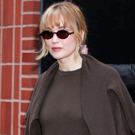 Jennifer Lawrence wore a button-down, a crewneck sweater, a wool jacket, and jeans with black-and-white Vans sneakers