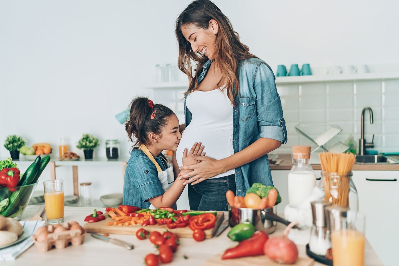 A woman deciding what to eat when pregnant with her daughter in the kitchen.