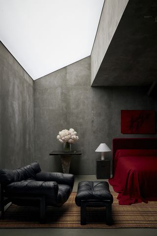 A bedroom with dark gray walls and bright red bedding