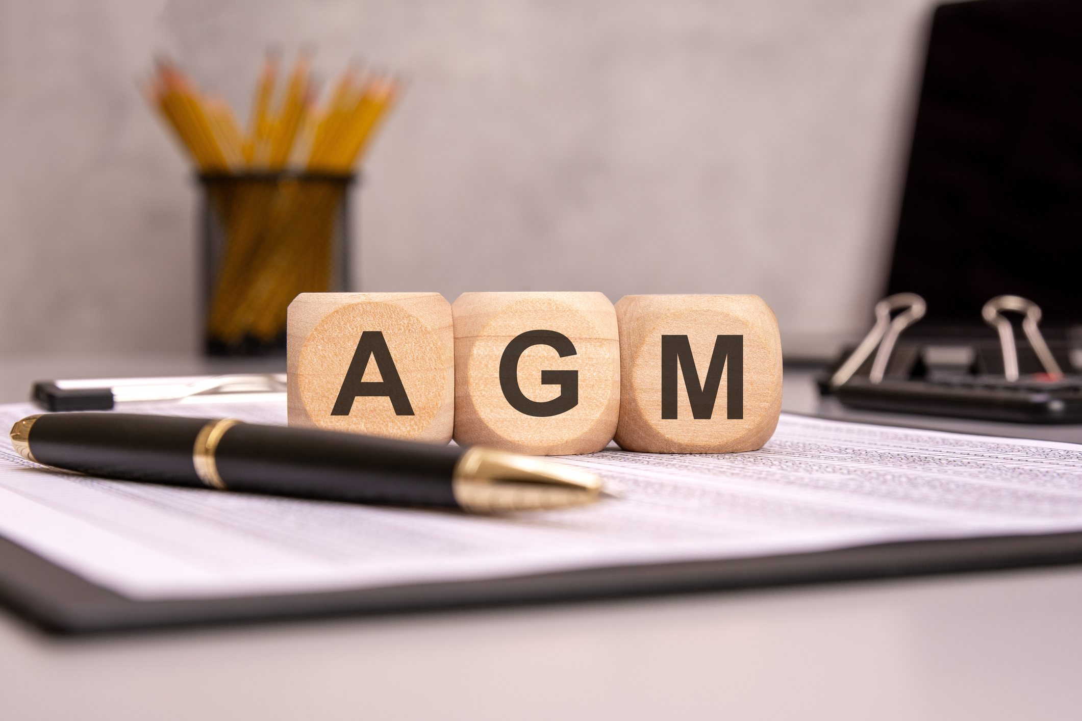 Wooden cubes spelling AGM on an office desk